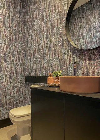 Foto de um banheiro com revestimento de parede estampado e bancada escura.