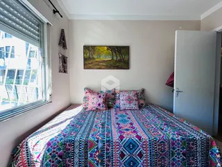 Quarto com cama decorada e janela iluminada.