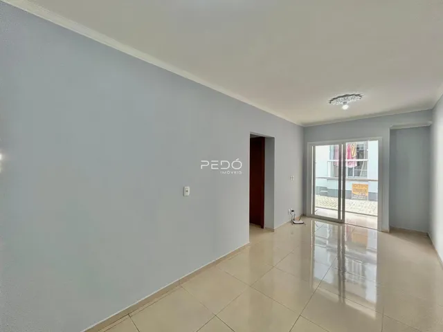 Espaço interno de uma residência com piso de cerâmica e portas de vidro.