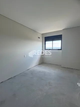 Ambiente interno de uma sala com paredes brancas e piso de concreto.