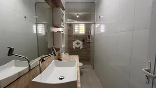 Banheiro com pias duplas e revestimento branco.