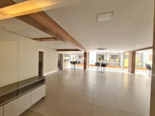 Sala de estar com pé direito alto e vigas de madeira no interior da residência.