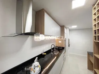 Foto de uma cozinha moderna com armários brancos e bancada escura.
