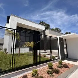 Fachada de uma residência moderna com revestimento branco e detalhes em preto.