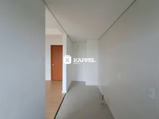 Corredor interno com piso de madeira e parede branca em uma residência.