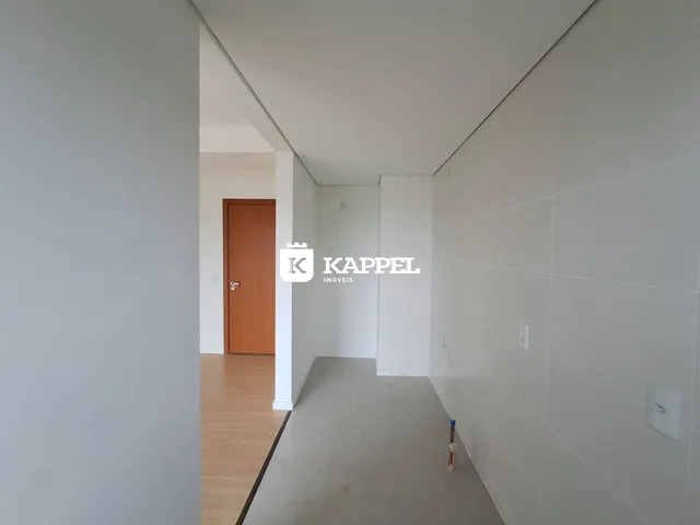 Corredor interno com piso de madeira e parede branca em uma residência.