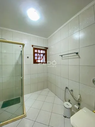 Foto de um banheiro com revestimento cerâmico e box de vidro.