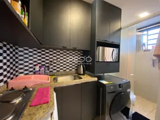 Cozinha com armários escuros e revestimento xadrez preto e branco.