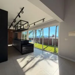 Sala de estar com grande abertura para o exterior e vista para o jardim.