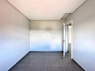Corredor interno com piso de cerâmica cinza e paredes brancas.