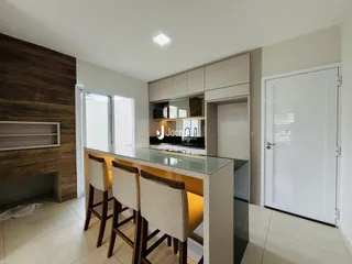 Sala de estar com cozinha moderna e ilha de vidro.