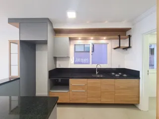Cozinha moderna com armários de madeira e bancadas escuras.