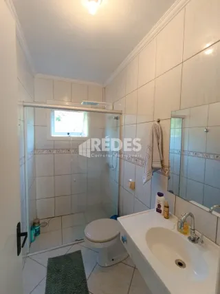 Foto de um banheiro interno com azulejos brancos e louças sanitárias.