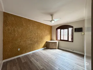 Quarto com parede decorada em dourado e piso de madeira clara.