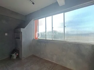 Interior de um ambiente com grande janela e paredes de concreto aparente.