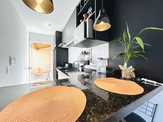Vista da cozinha moderna com bancada escura e armários brancos.