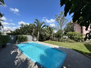 Foto de uma piscina externa cercada por gramado e vegetação.