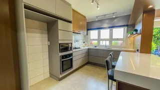 Vista da cozinha moderna com armários cinzas e piso claro.