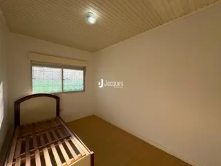 Quarto com piso de madeira e paredes brancas em um imóvel no Brasil.