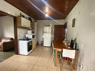 Interior de uma sala de estar com cozinha em um imóvel no Brasil.