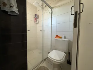 Foto interna de um banheiro com revestimento cerâmico e box de vidro.