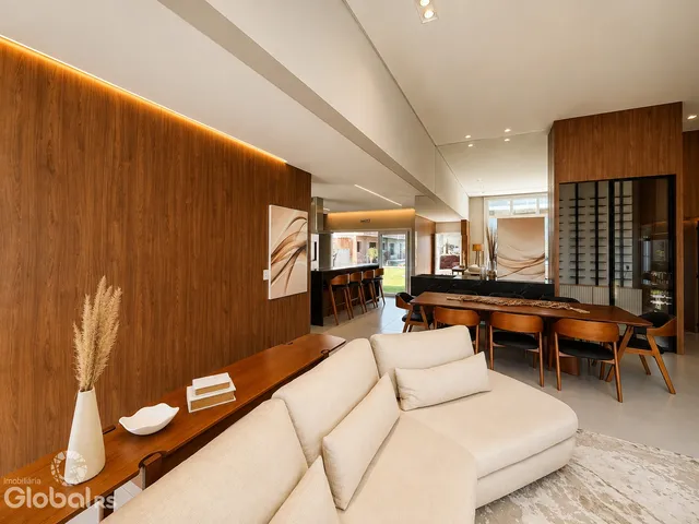 Sala de estar moderna com sofá grande e painéis de madeira em um apartamento em Lajeado.