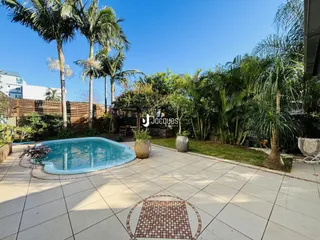 Área externa com piscina e jardim tropical no quintal.