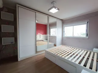 Quarto com armários e cama de madeira clara em um apartamento.