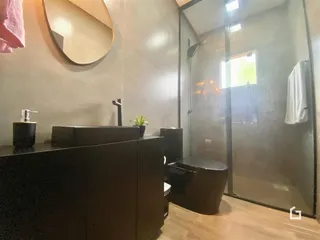 Foto de um banheiro com box de vidro e bancada escura.