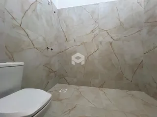 A foto mostra o interior de um banheiro com revestimento de mármore.