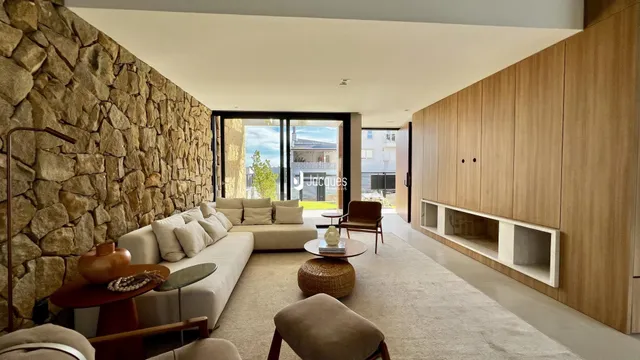 Sala de estar moderna com parede de pedra e painéis de madeira.