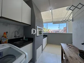 Vista interna de uma cozinha com armários brancos e bancada escura.