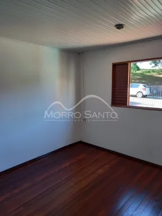 Foto interna de um cômodo com piso de madeira escura e teto branco.