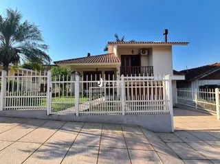 A fachada de uma casa em Lajeado, Brasil, com cerca branca e portão.
