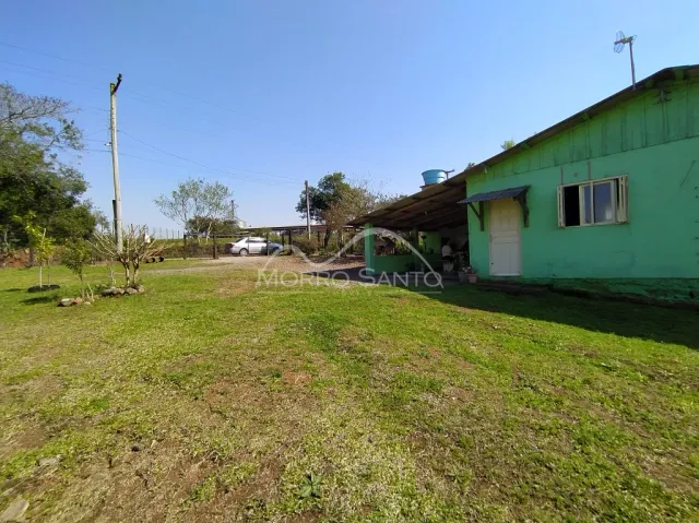 Vista externa de uma propriedade com gramado e vegetação ao redor.
