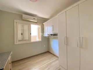 Interior de um ambiente com piso de madeira clara e armários brancos.