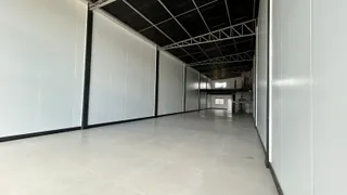 Corredor interno com paredes brancas e teto exposto.