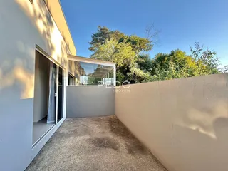 Fachada lateral de uma residência com parede e vegetação ao fundo.