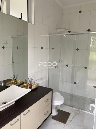 Banheiro moderno com revestimento branco e box de vidro.