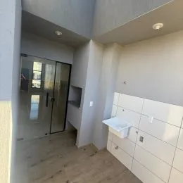 Corredor com piso de madeira e portas de vidro.