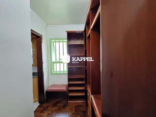 Hall de entrada com piso de madeira e estante de madeira visível.