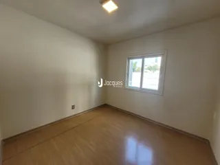 Uma sala de estar com piso de madeira clara e paredes brancas.
