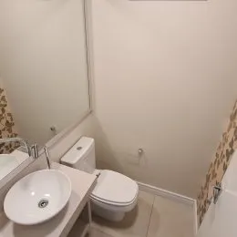 Foto de um banheiro com louças brancas e revestimento claro.