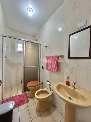 Foto de um banheiro com azulejos brancos e louças de cor bege.