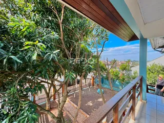 Vista da varanda com vegetação exuberante e paisagem ao fundo.