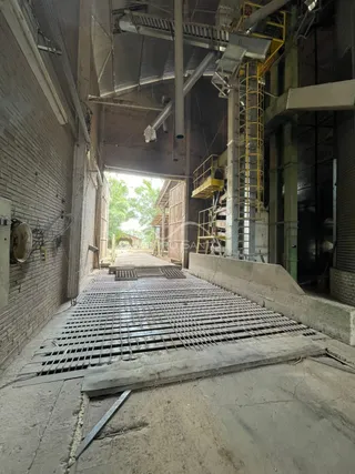 Foto de uma área estrutural em construção com piso de malha metálica.