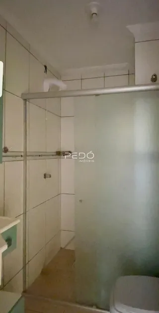 Interior de um banheiro com paredes brancas e box de vidro.