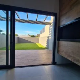 Vista de um ambiente interno com acesso a uma área externa com gramado.