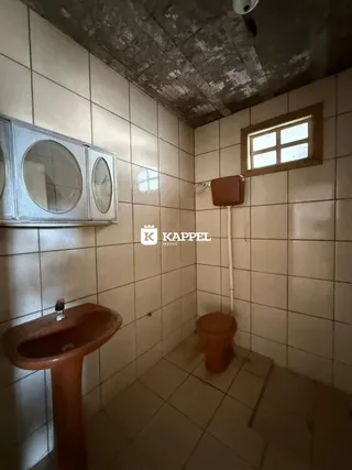 Banheiro com paredes de azulejo e pia de cor marrom.