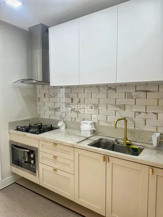 Foto de uma cozinha com armários brancos e bancada clara.